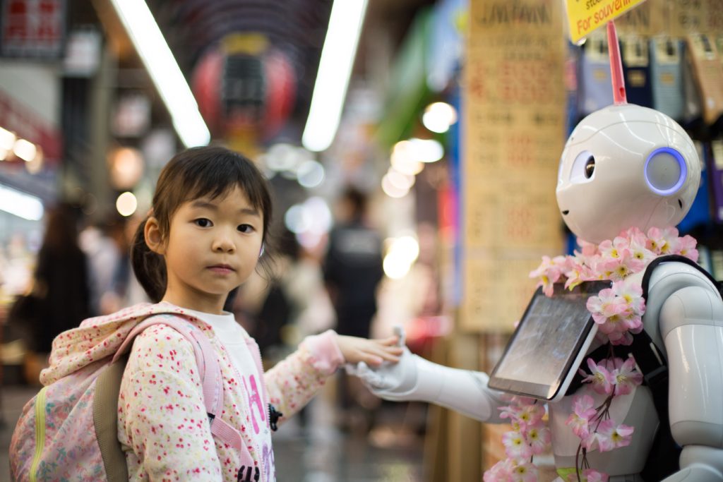 A little girl touches the hand of a robot of a robot