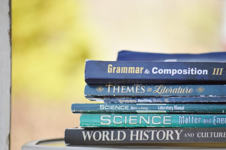 Stack of textbooks on a table with a blurred background.